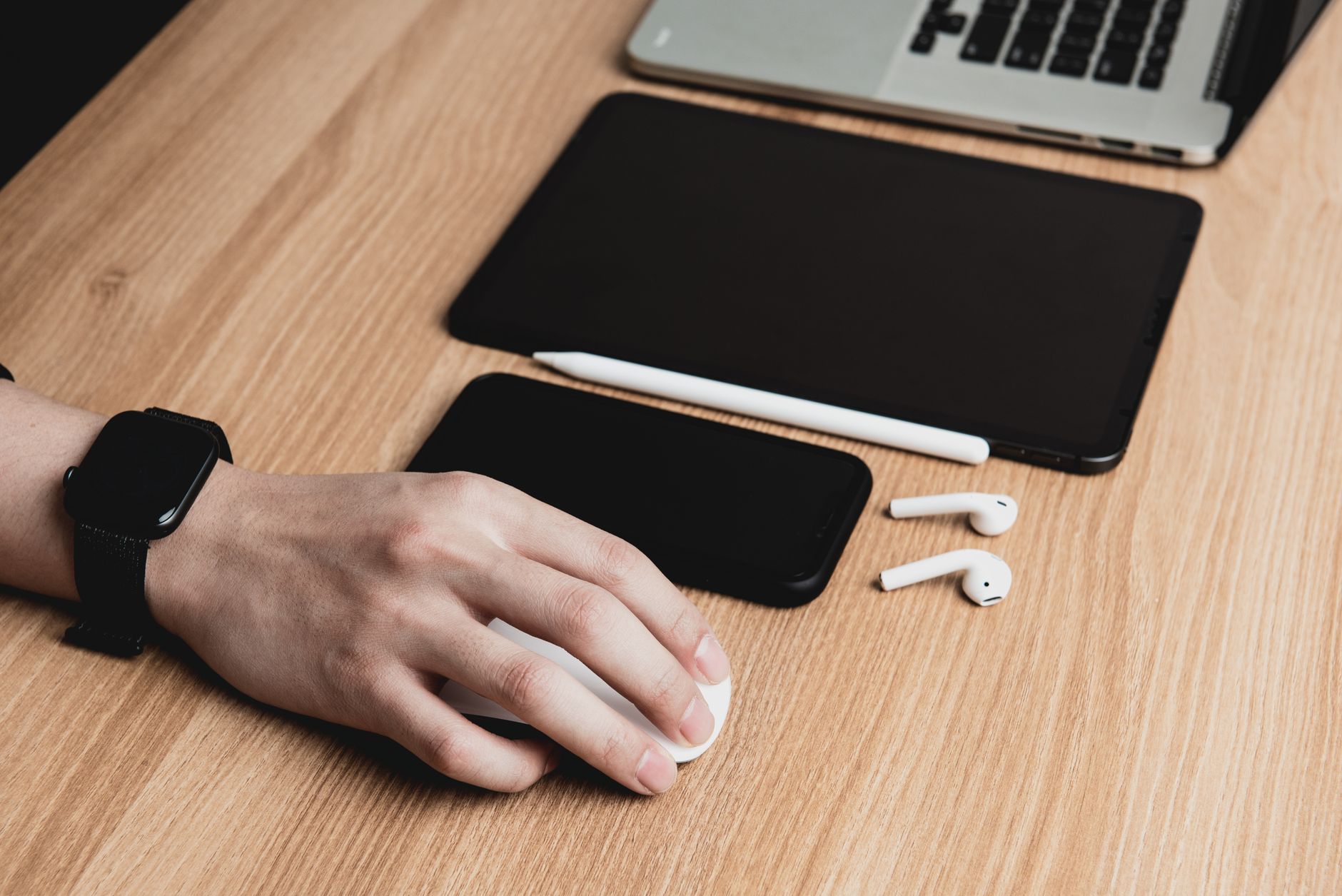 Person's hand resting on a black vertical ergonomic mouse next to a keyboard