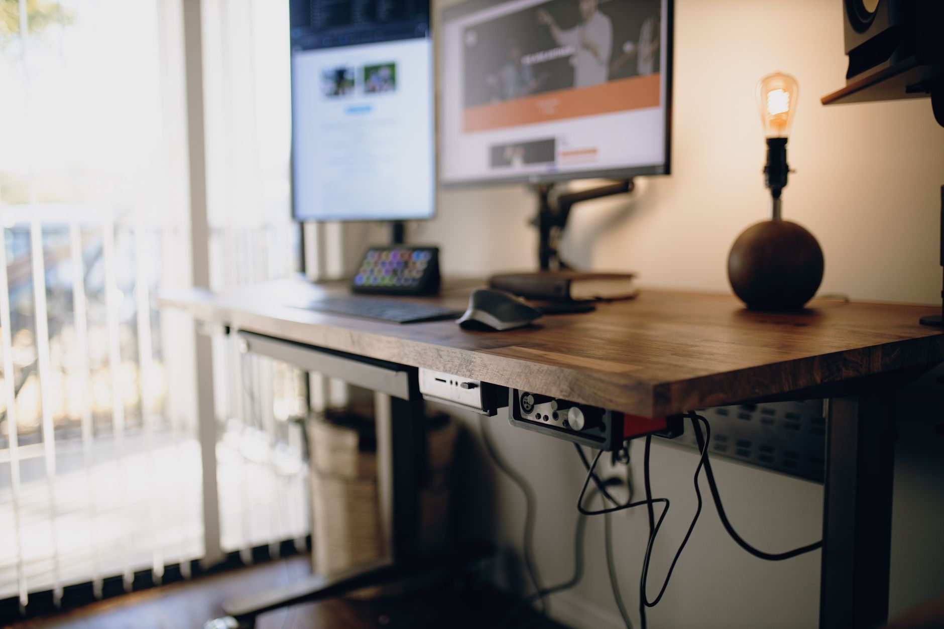 Keyboard tray mounted under a wooden office desk with a black keyboard resting on the platform